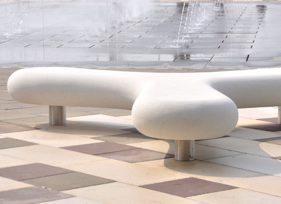 Geschwungenes Sitzelement aus Beton mit Stehern aus Metall als Hingucker im Außenbereich
